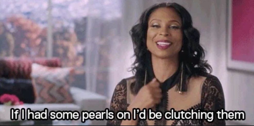 Woman smiling, wearing a lace dress, gestures as subtitle reads: "If I had some pearls on I'd be clutching them."