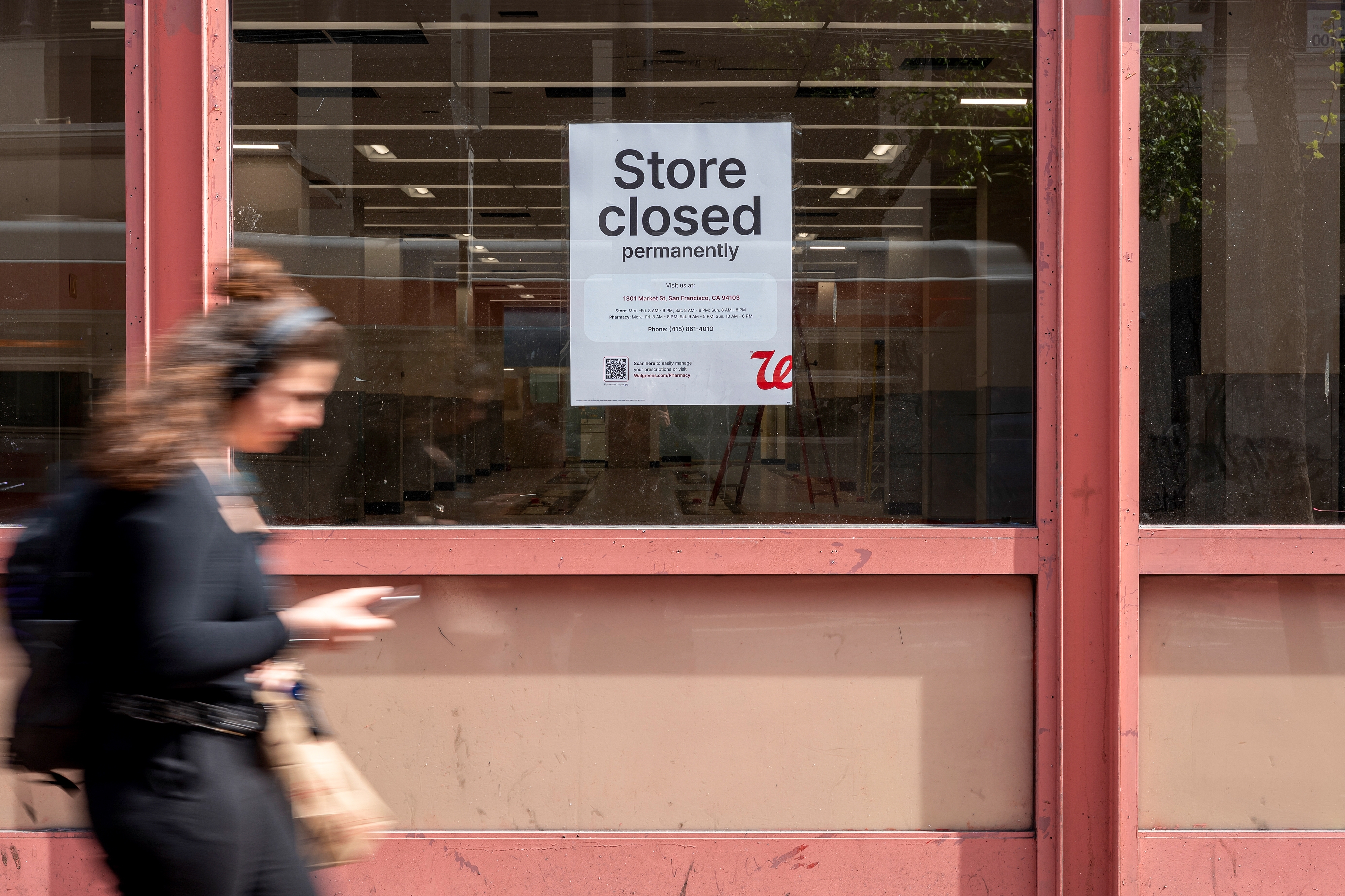 A person walks past a storefront with a sign reading &quot;Store closed permanently&quot; displayed on the window