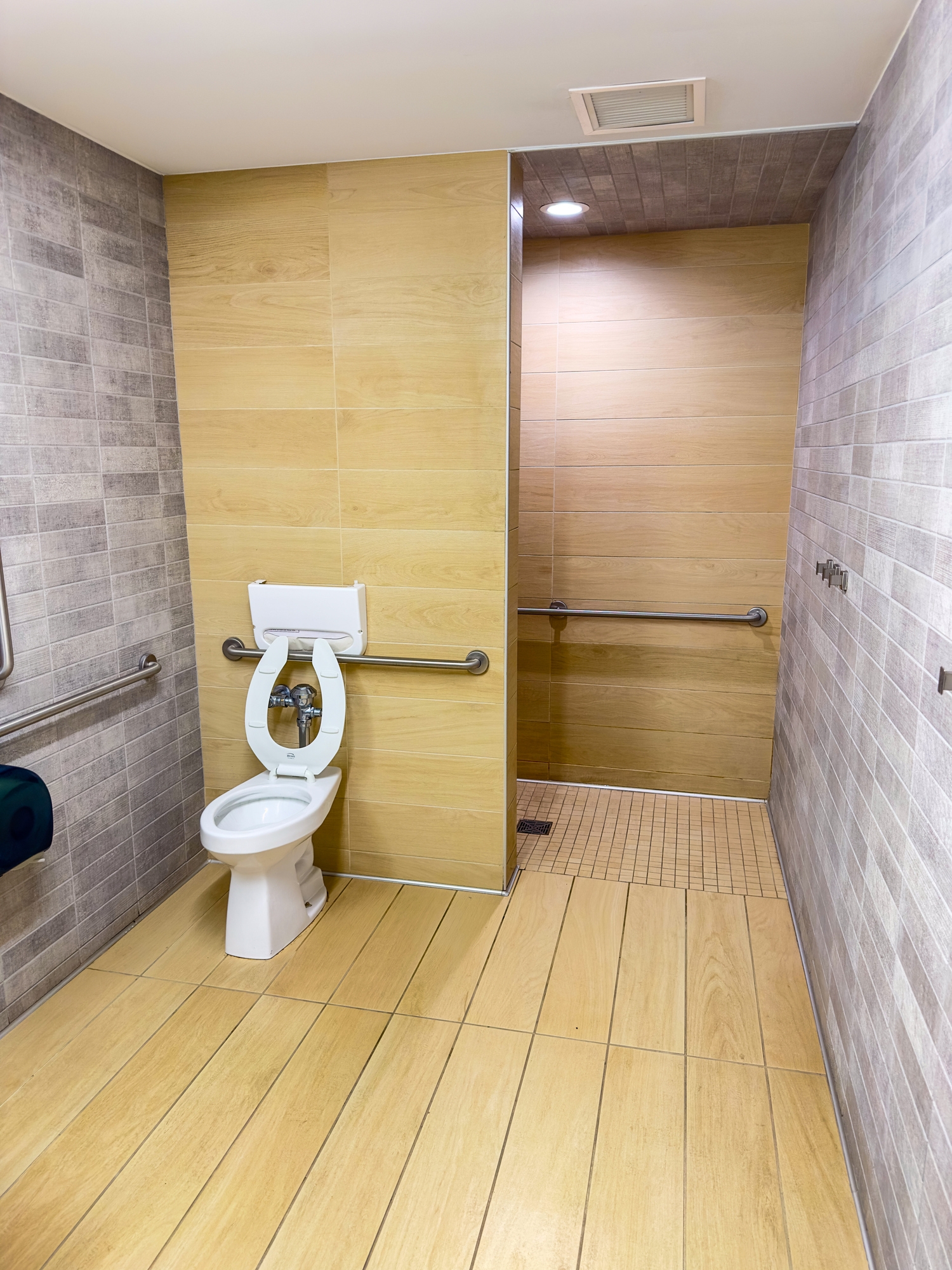 Accessible restroom with wide space, handrails near the toilet and shower area