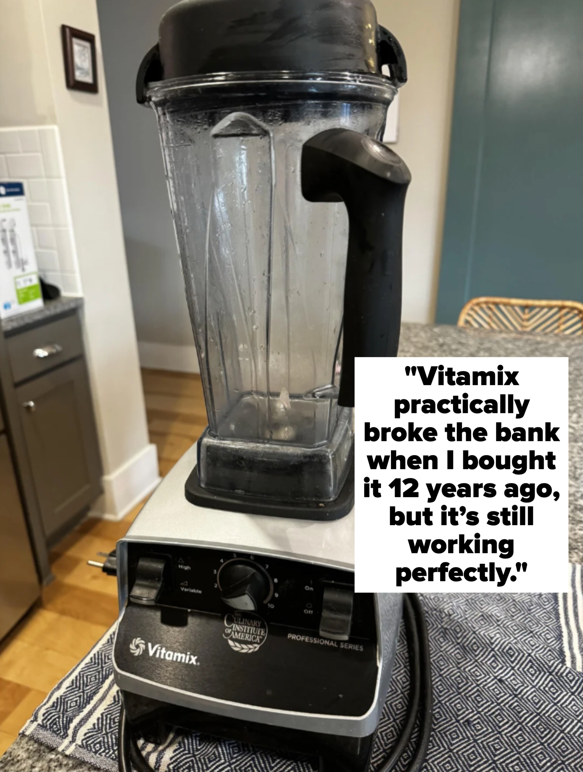 A professional-grade blender on a kitchen countertop, unplugged, with a clear container and black handle