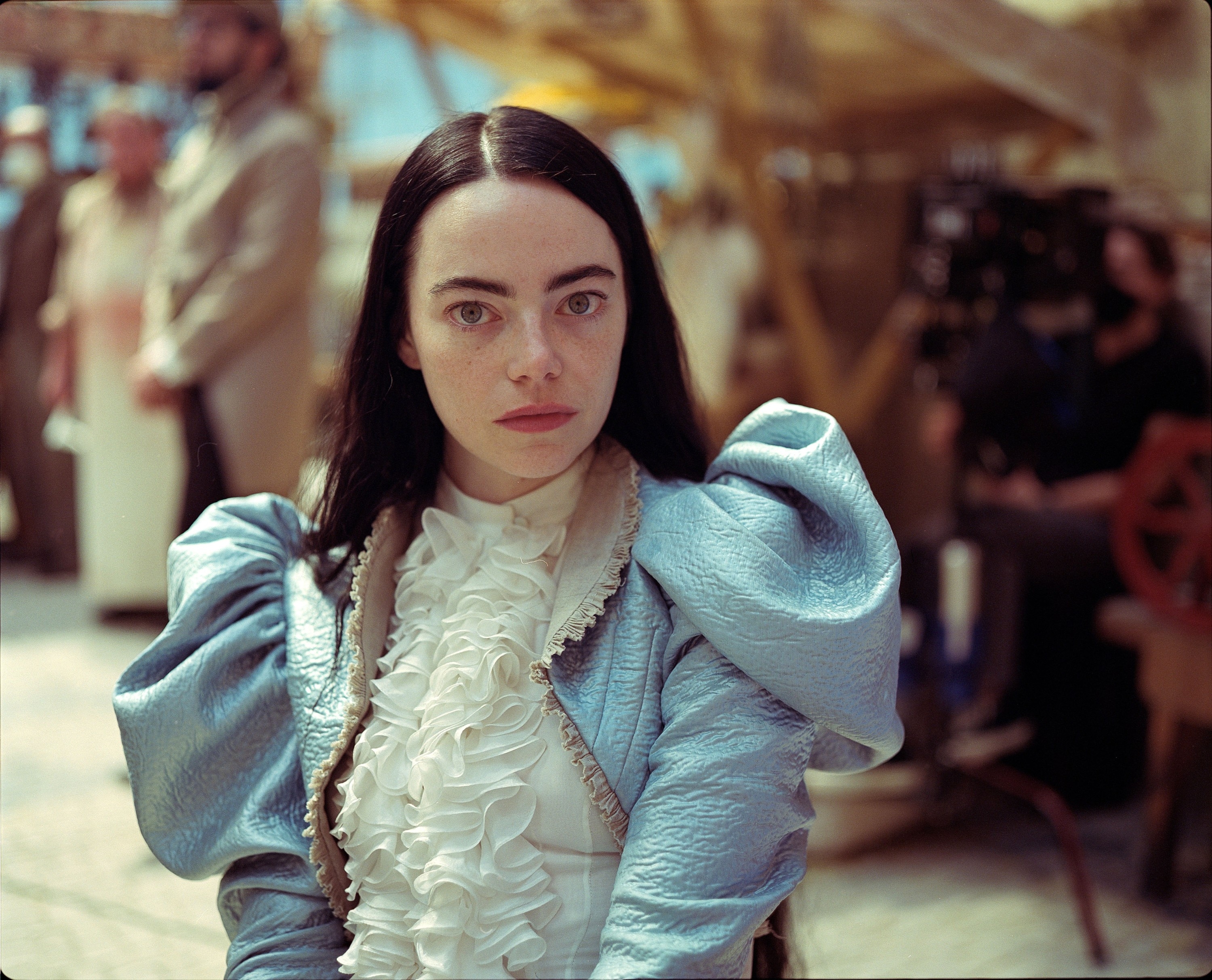 Emma Stone as Bella standing on a film set