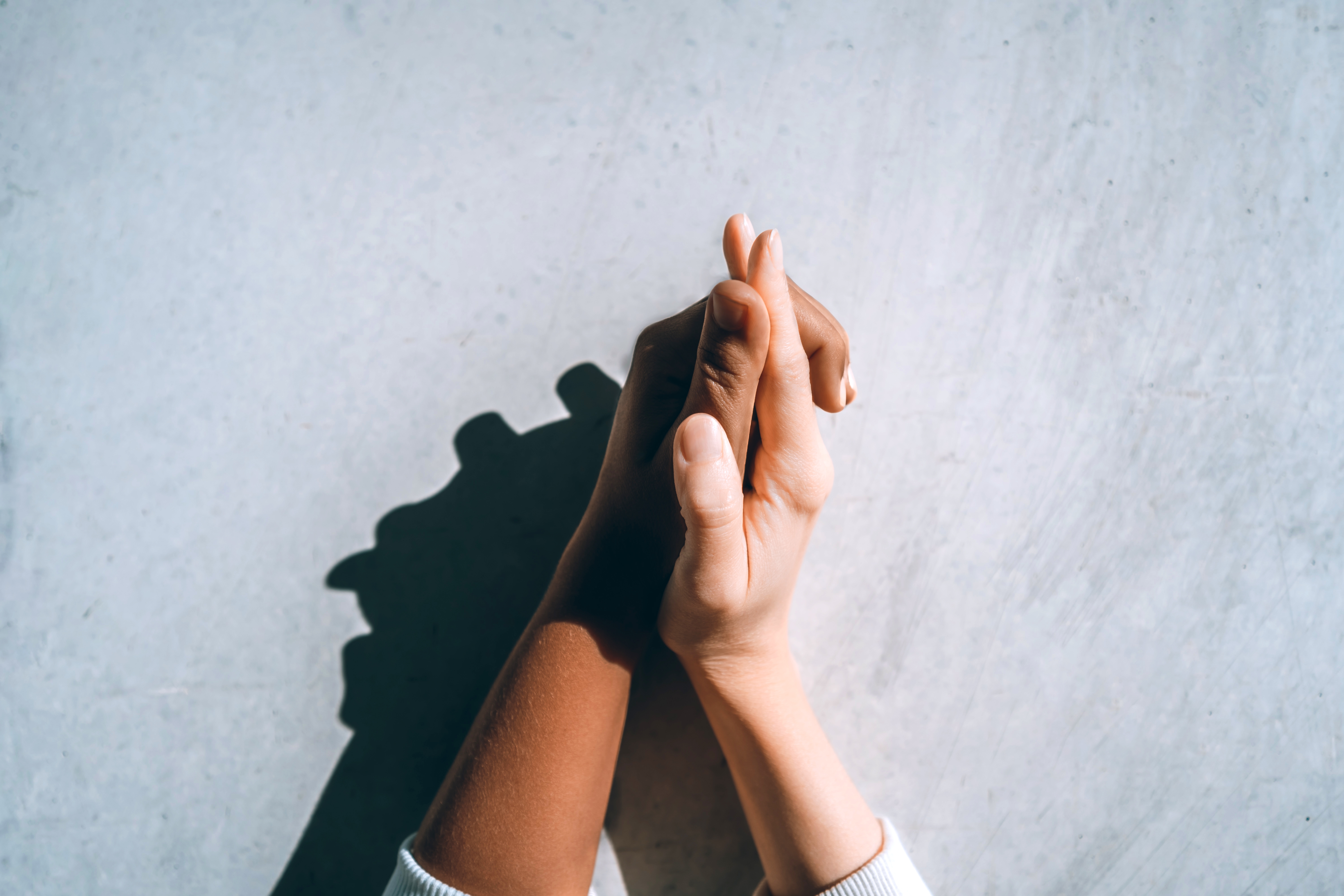 Two hands gently clasped together, with one slightly darker than the other, symbolizing connection and intimacy