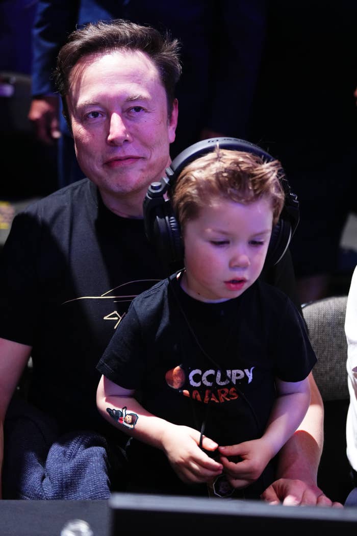 An adult and child sit together, both wearing headphones. The child wears an 