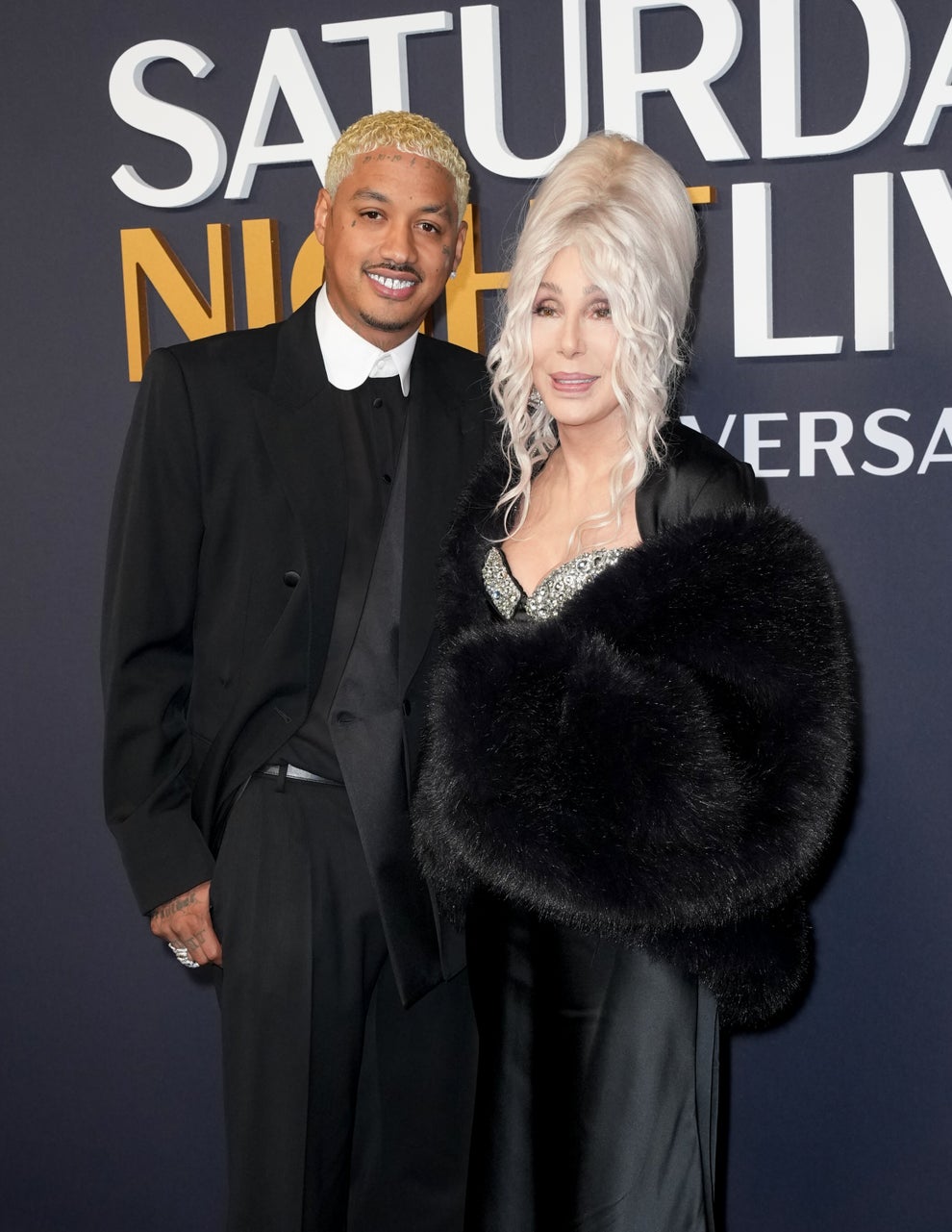 24 Bizarre Celeb Facts That Sound Fake, But Are 100% True 42 A man in a black suit poses with a woman in an elegant black dress and fur stole, both smiling at a "Saturday Night Live" event backdrop