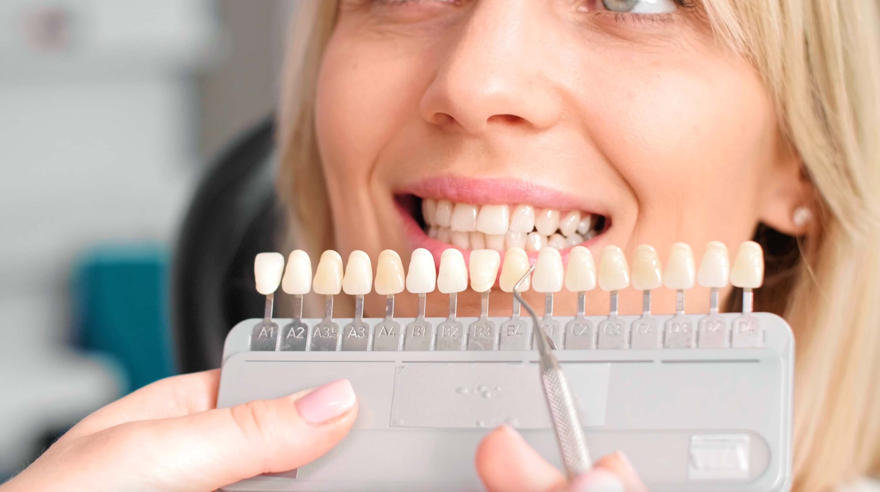 Person som smiler mens du sammenligner tannfargeskjermer ved hjelp av en tannlege guide
