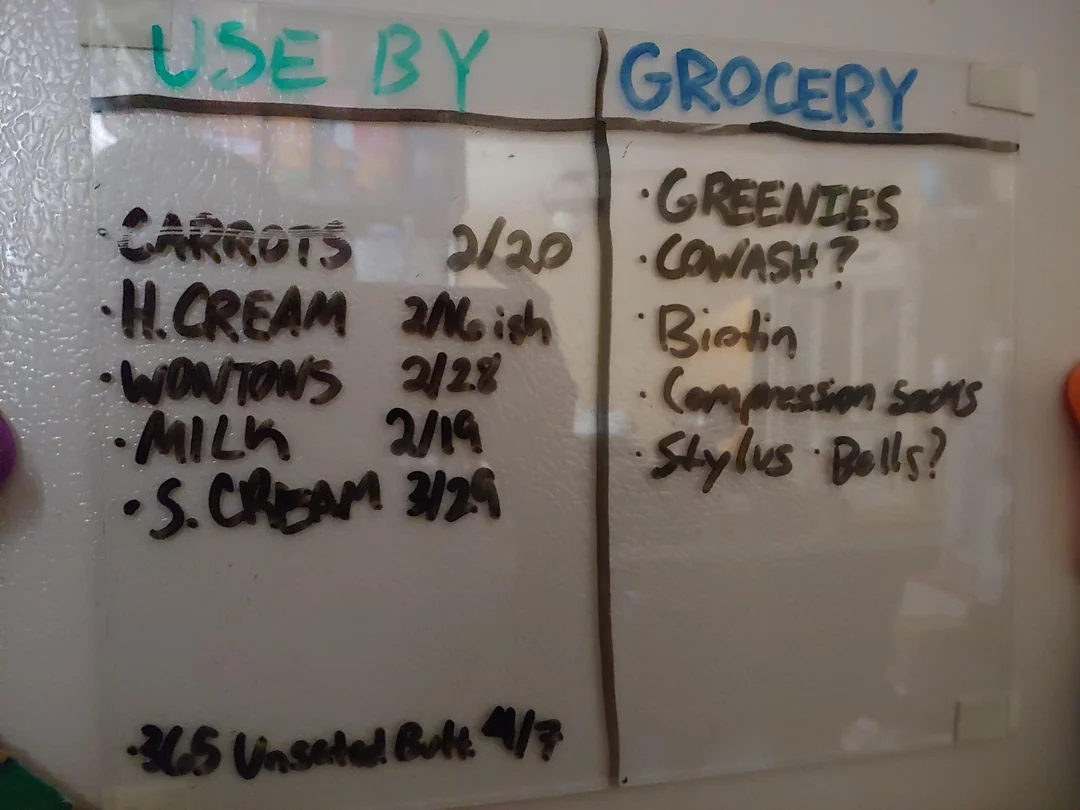 Whiteboard with two lists: "Use By" includes carrots, heavy cream, wontons, milk, sour cream; "Grocery" lists greenies, squash, biotin, socks, stylus, bowl