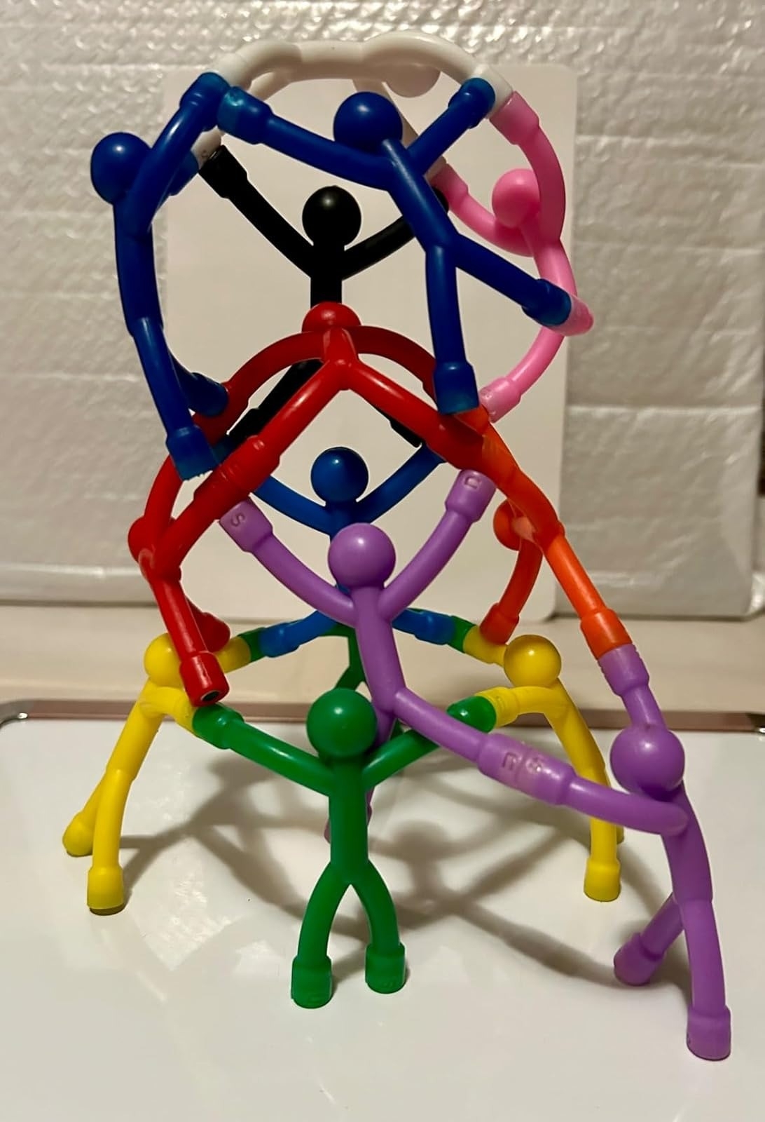 Toy figures connect to form a colorful human pyramid, illustrating creative possibilities for playful assembly