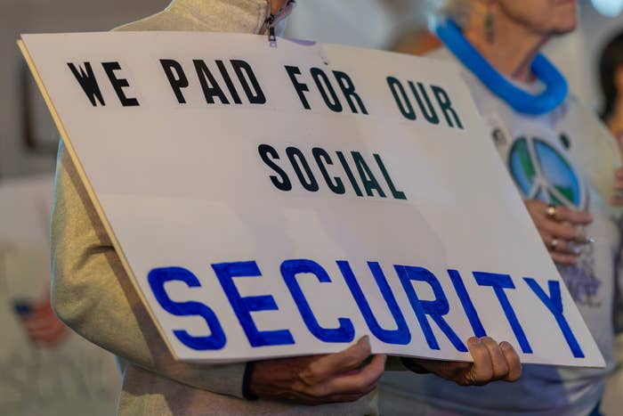 Elderly man at a protest holds a sign saying, "We paid for our social security," highlighting concerns about pensions