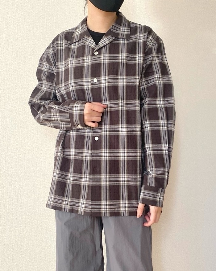 モデルがチェック柄のシャツとパンツを着用し、手を前に置いているスタイルのイメージ。