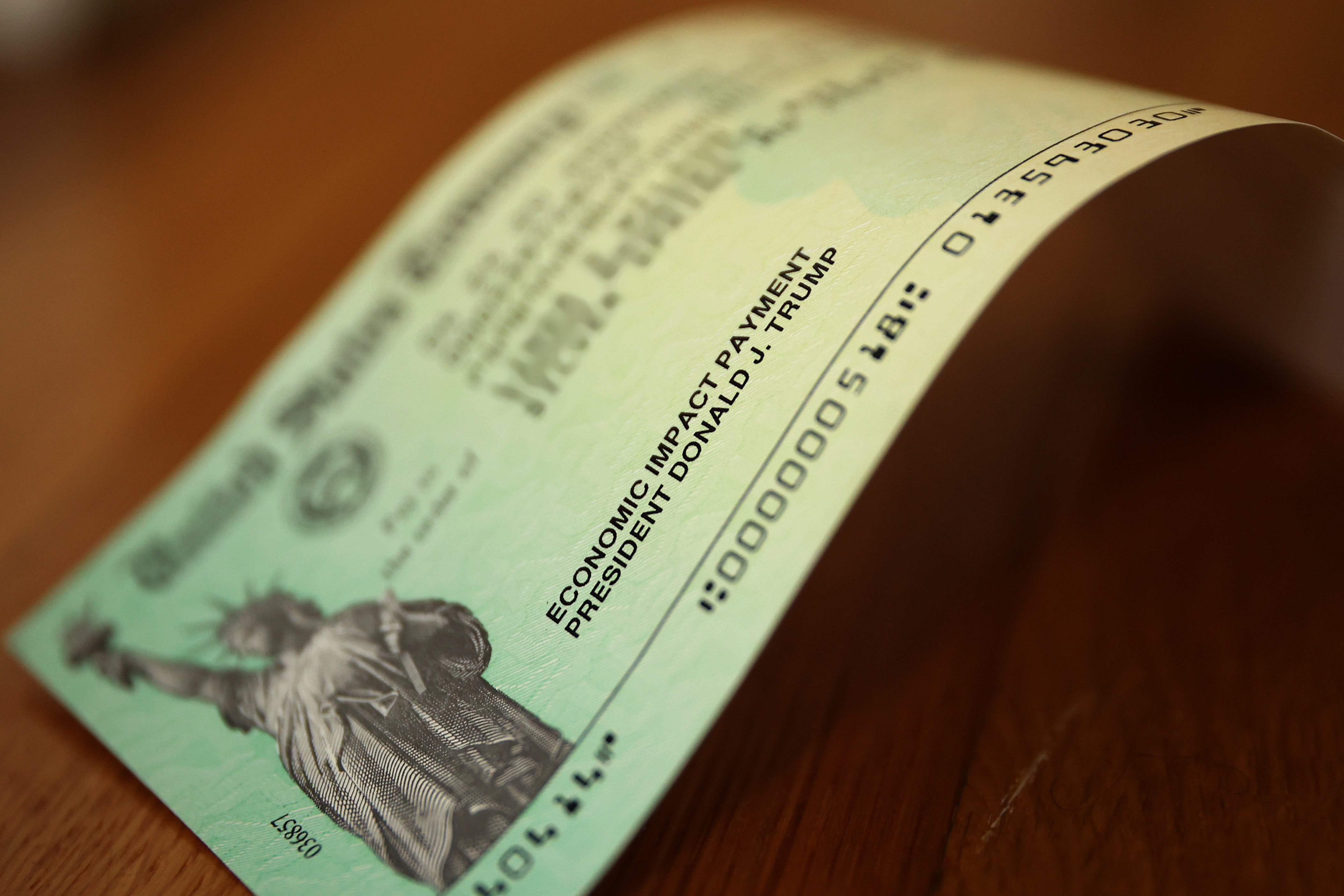 Close-up of a U.S. Economic Impact Payment check, featuring text indicating it is from President Donald J. Trump, with the Statue of Liberty image