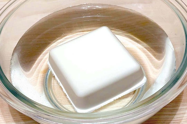 ガラスのボウルに透明の液体と四角い物体が浮いている様子。