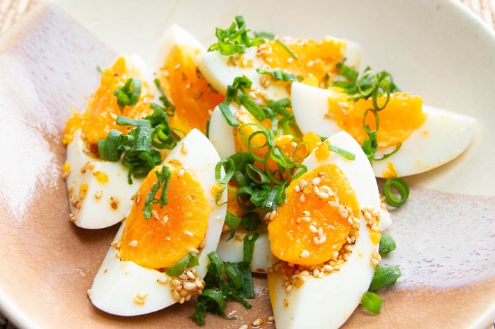 半熟卵のサラダ、ねぎとごまをトッピングした盛り付けが美しい料理。