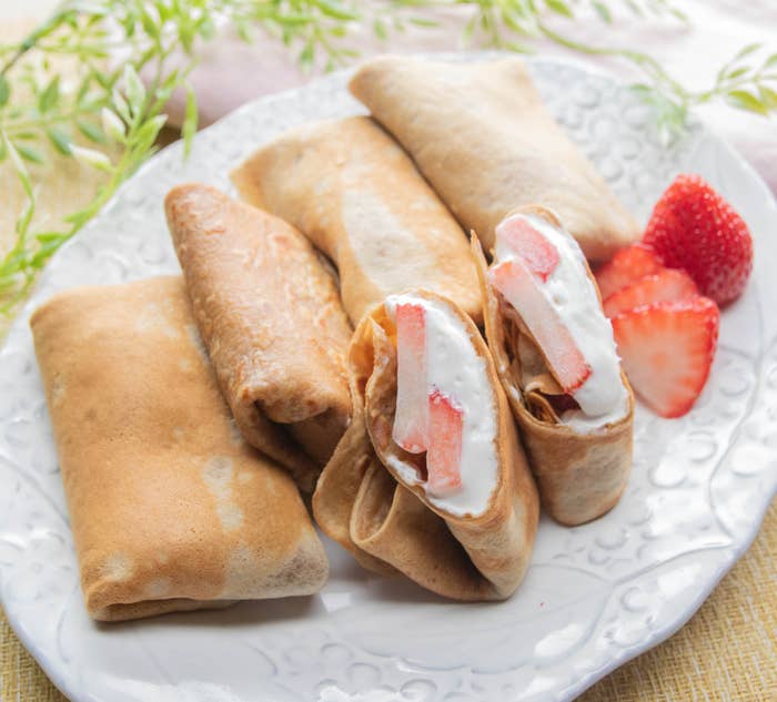皿の上に盛り付けられた数個のクレープには、クリームといちごの具が見える。