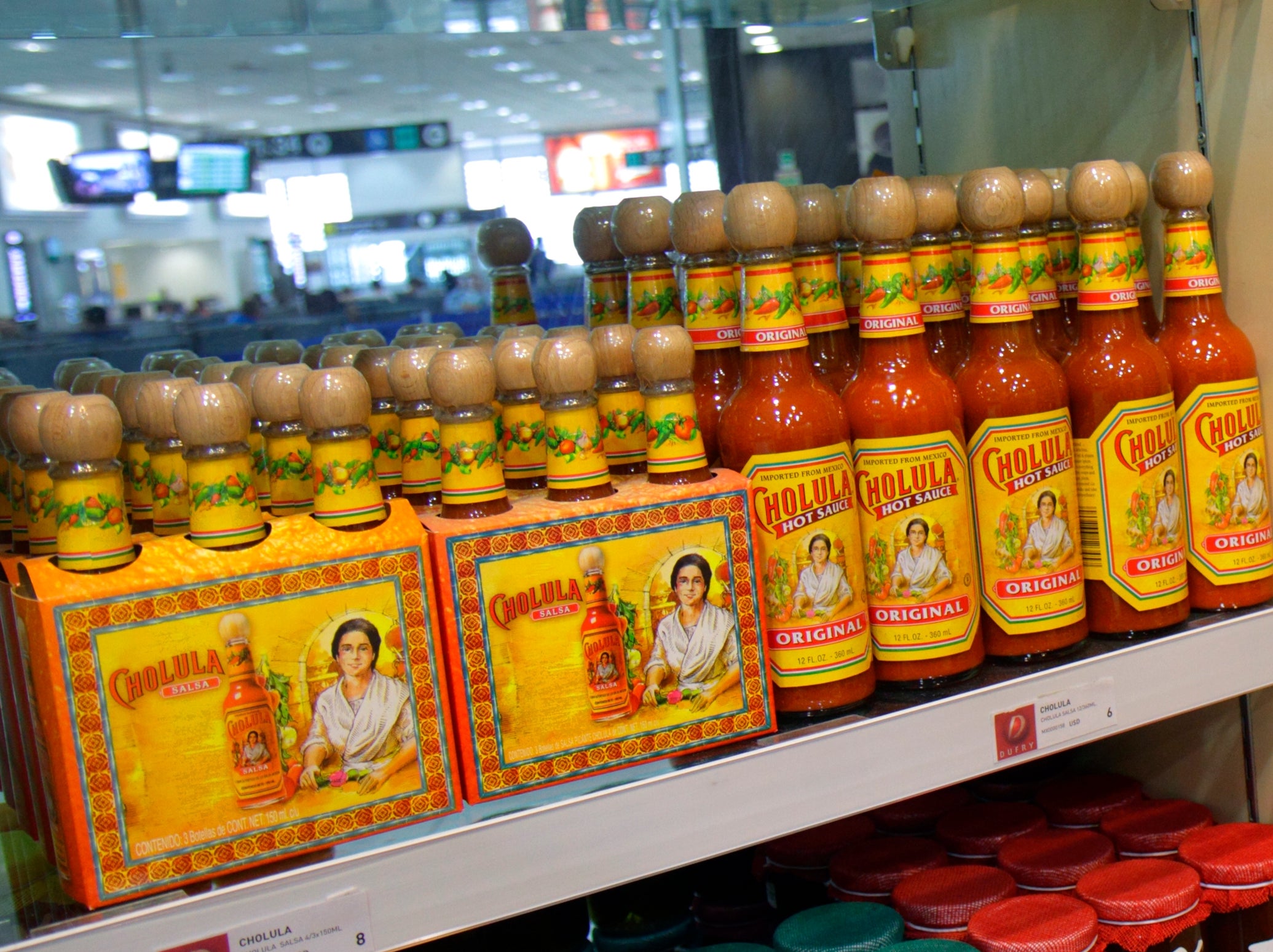 Grocery store shelves display various sauces, olive oils, and pickled goods in colorful jars and bottles, highlighting diverse food products