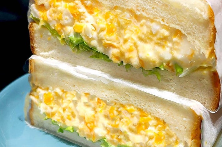 2つに切られた卵サンドイッチが皿に載っている。卵とマヨネーズのフィリングがたっぷり詰まっている。