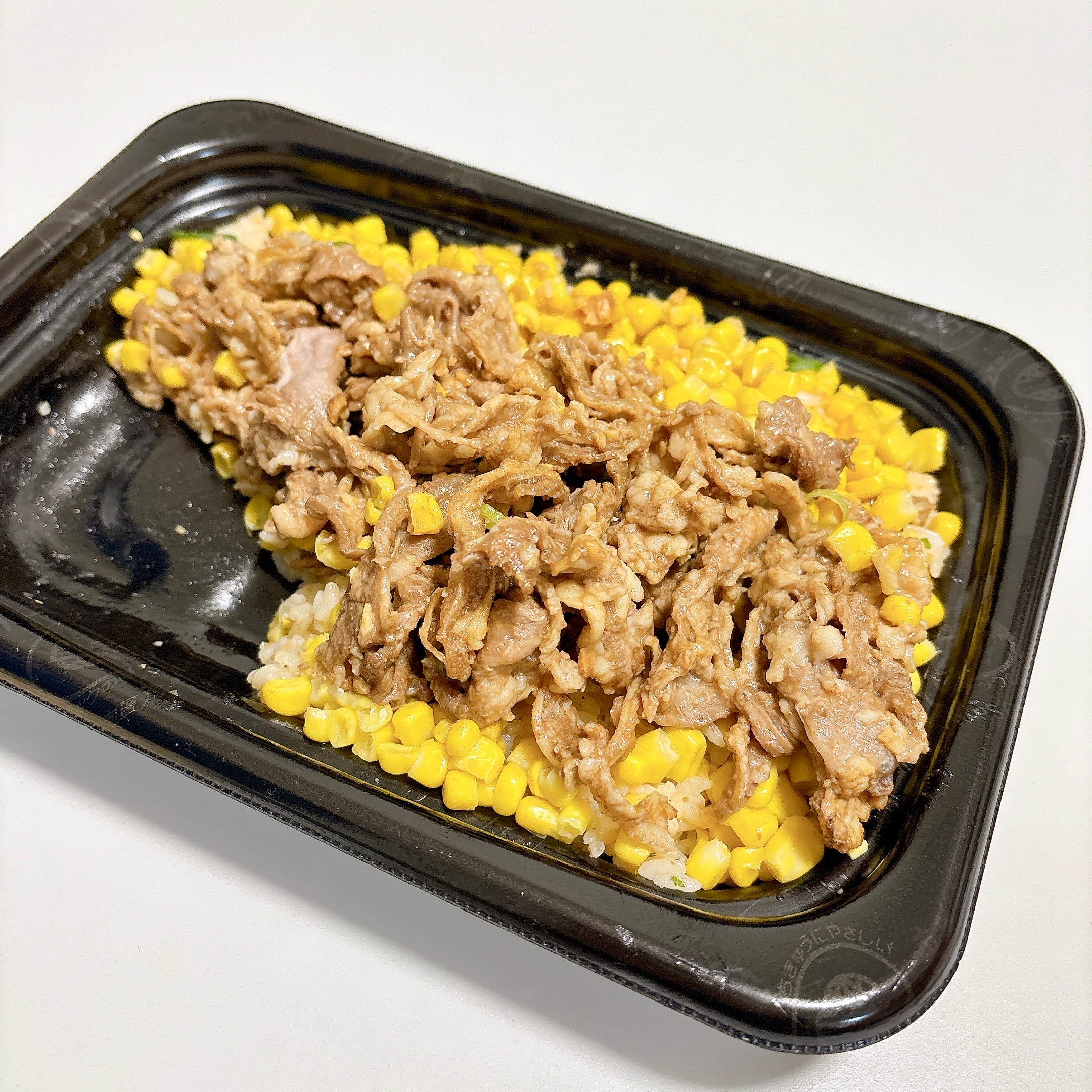 黒い容器に入った牛肉とコーンがのったご飯。
