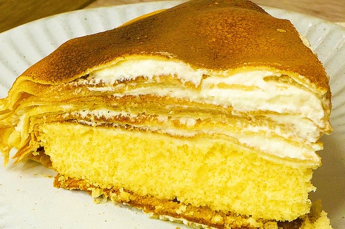 ケーキの断面の写真。複数の薄いスポンジとクリームの層が重なり、滑らかな質感が際立つデザートです。