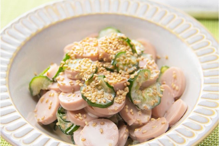 きゅうりとソーセージのサラダが白い皿に盛られ、ゴマがトッピングされている。