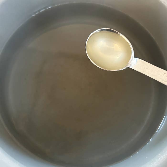 鍋の中の液体に、大さじ1杯の透明な液体が加えられようとしている様子。