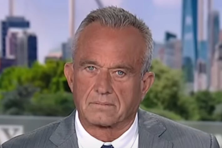 A person in a suit is seen outdoors with a blurred cityscape in the background