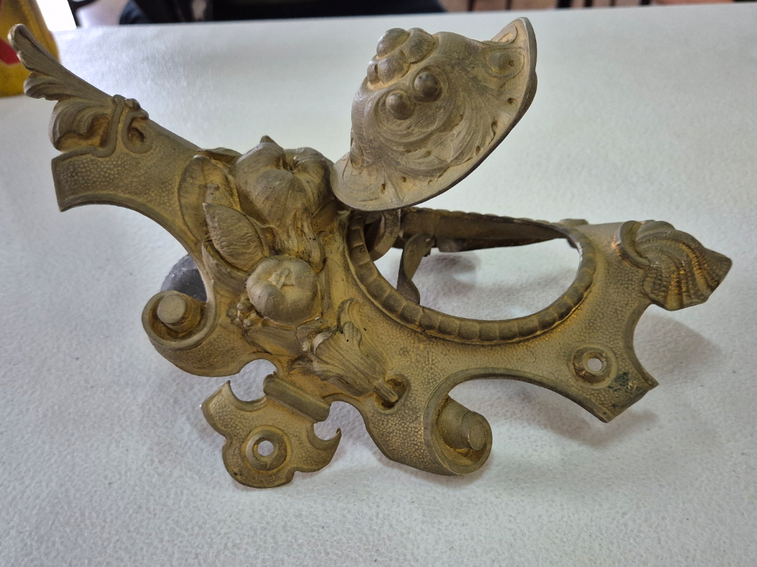 Ornate, vintage metal sculpture featuring a detailed dragon design, displayed on a flat surface