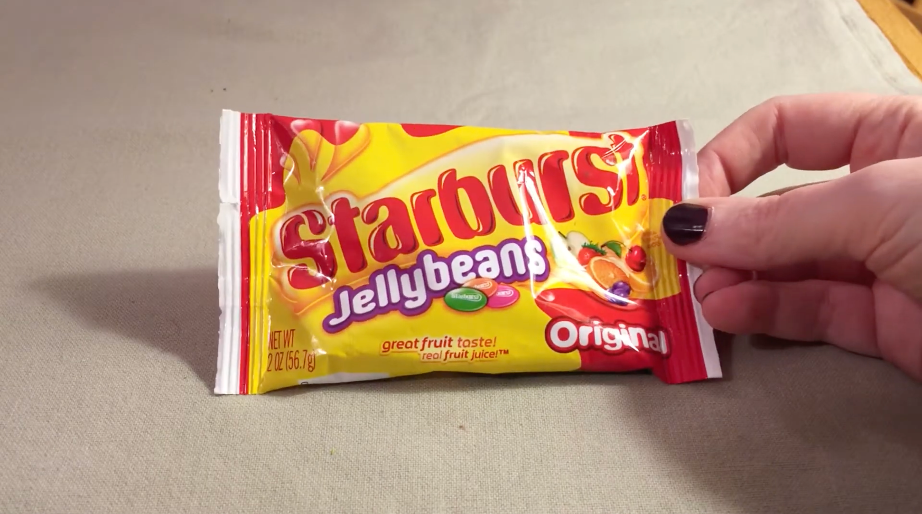 Someone holding a package of Starburst Jellybeans with a partial view of their hand