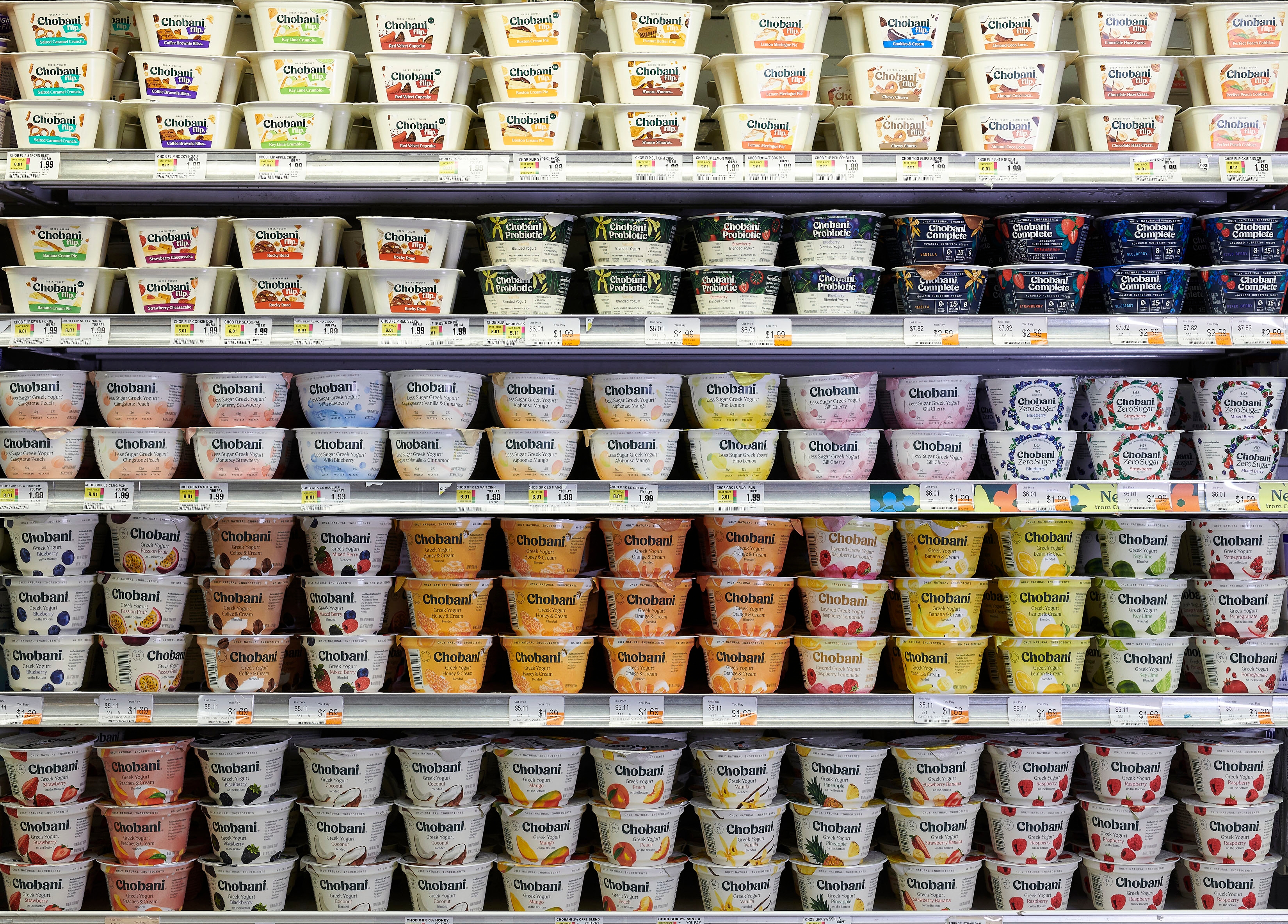 Grocery store shelf filled with various flavors of Chobani yogurt in neatly arranged rows