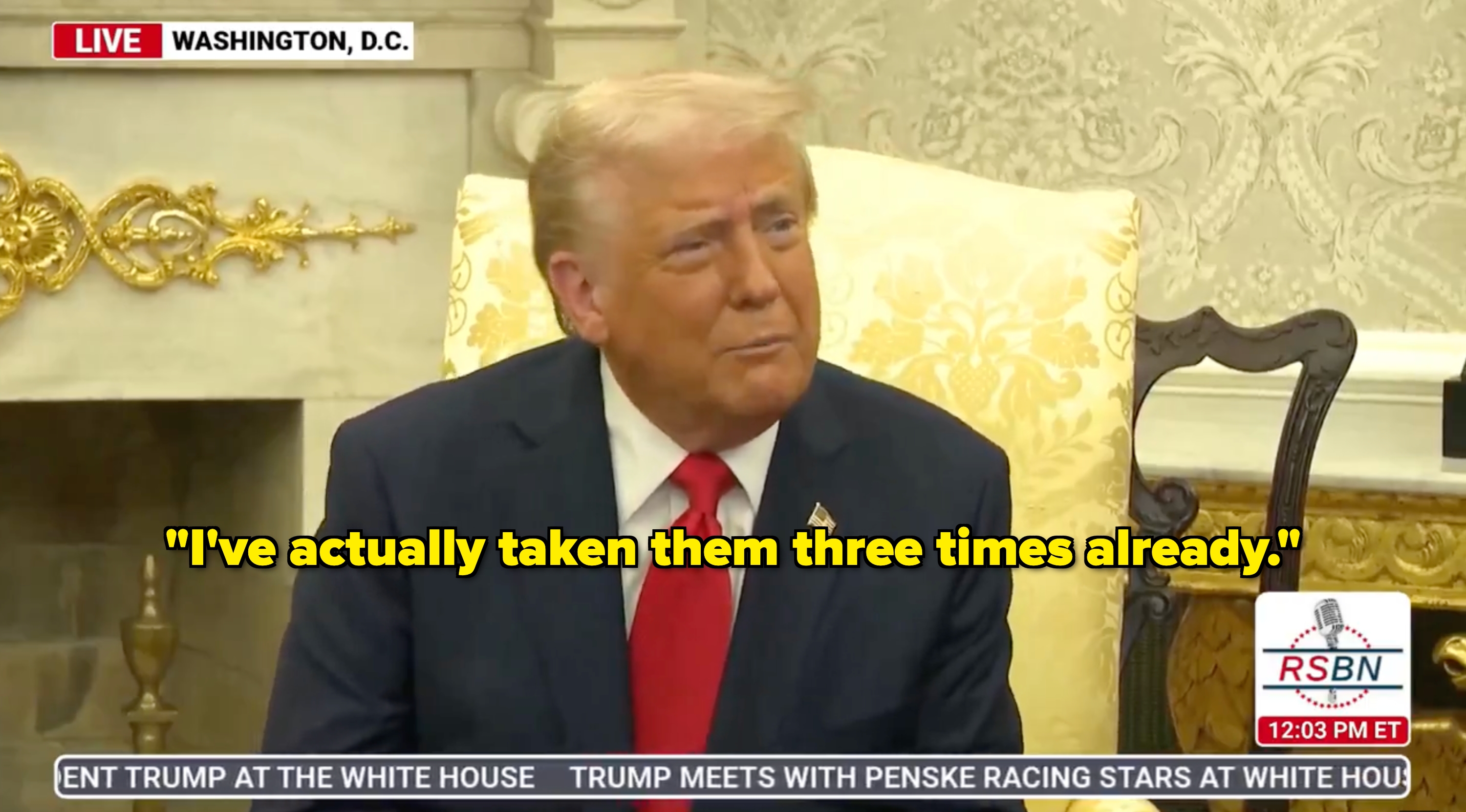 A person in a suit with a red tie sits in a formal setting, appearing to listen attentively. News ticker at bottom references a meeting