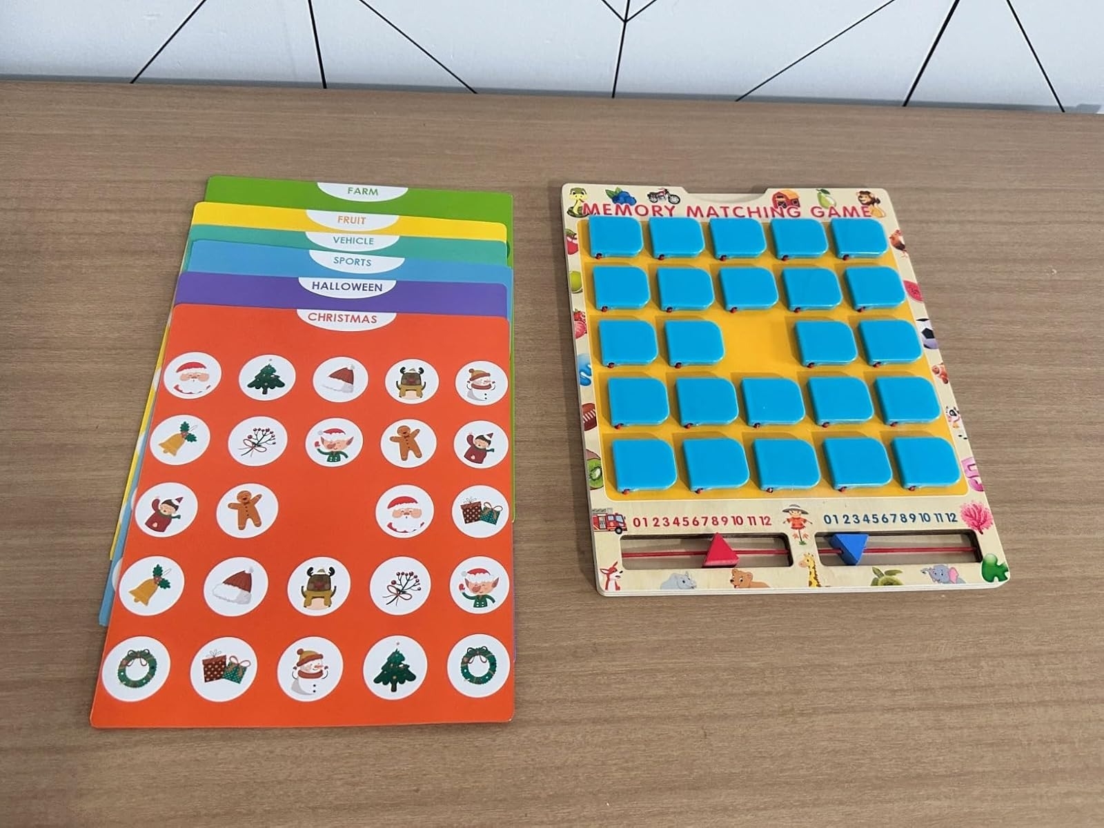 Memory game set with themed cards labeled farm, fruit, vehicle, sports, Halloween, and Christmas, alongside a grid board with blue tiles