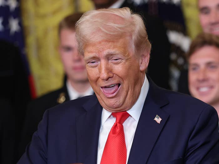 Person in a suit holding a football and a ring, smiling, surrounded by people in formal attire at an event