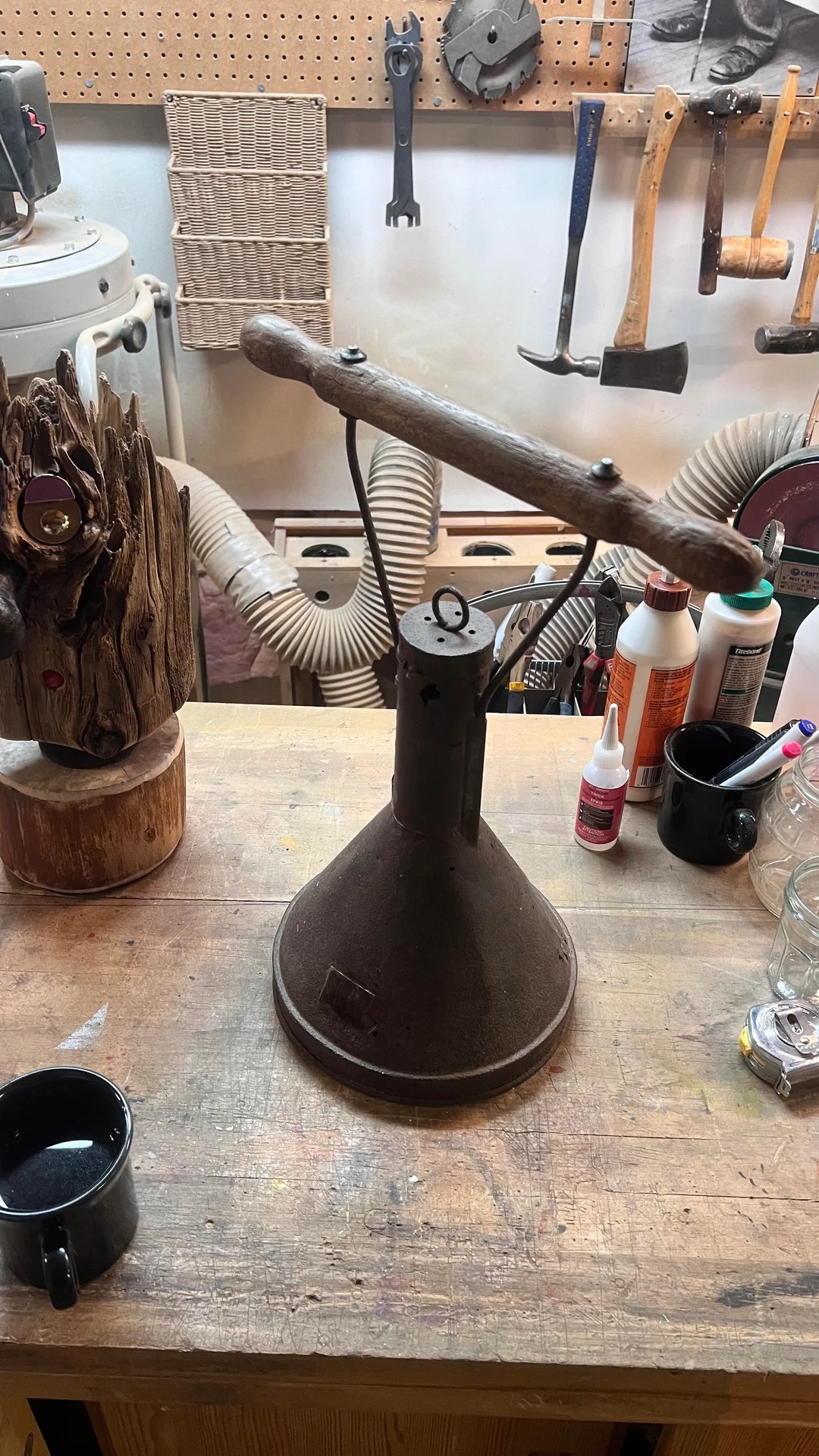 Woodworking workshop with tools, glue bottles, a wooden sculpture on a table, and a vintage lamp centerpiece