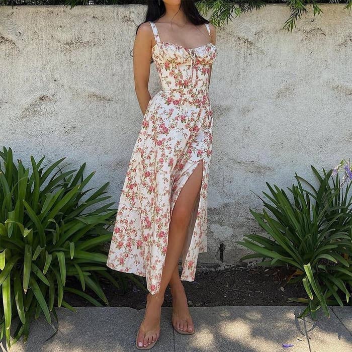 Person modeling a floral formal  with a slit, lasting  successful  a plot  setting. The formal  is sleeveless with a fitted bodice
