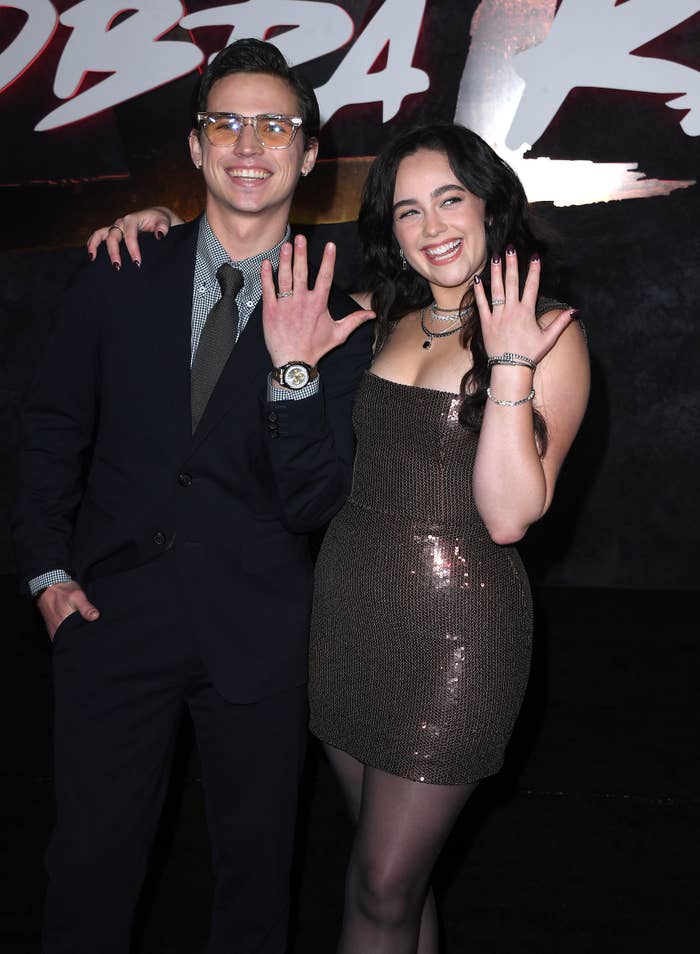 Tanner and Mary showing off their matching rings on a red carpet