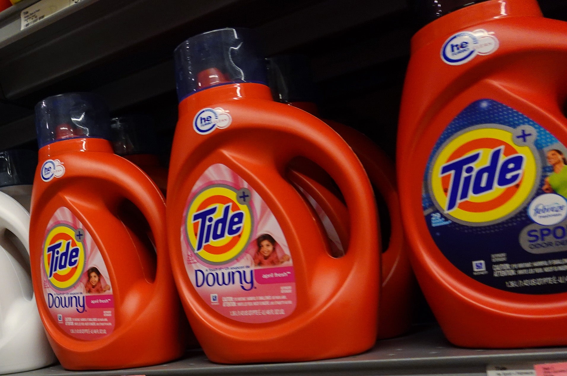 Shelves stocked with various Tide detergent bottles, with price tags visible