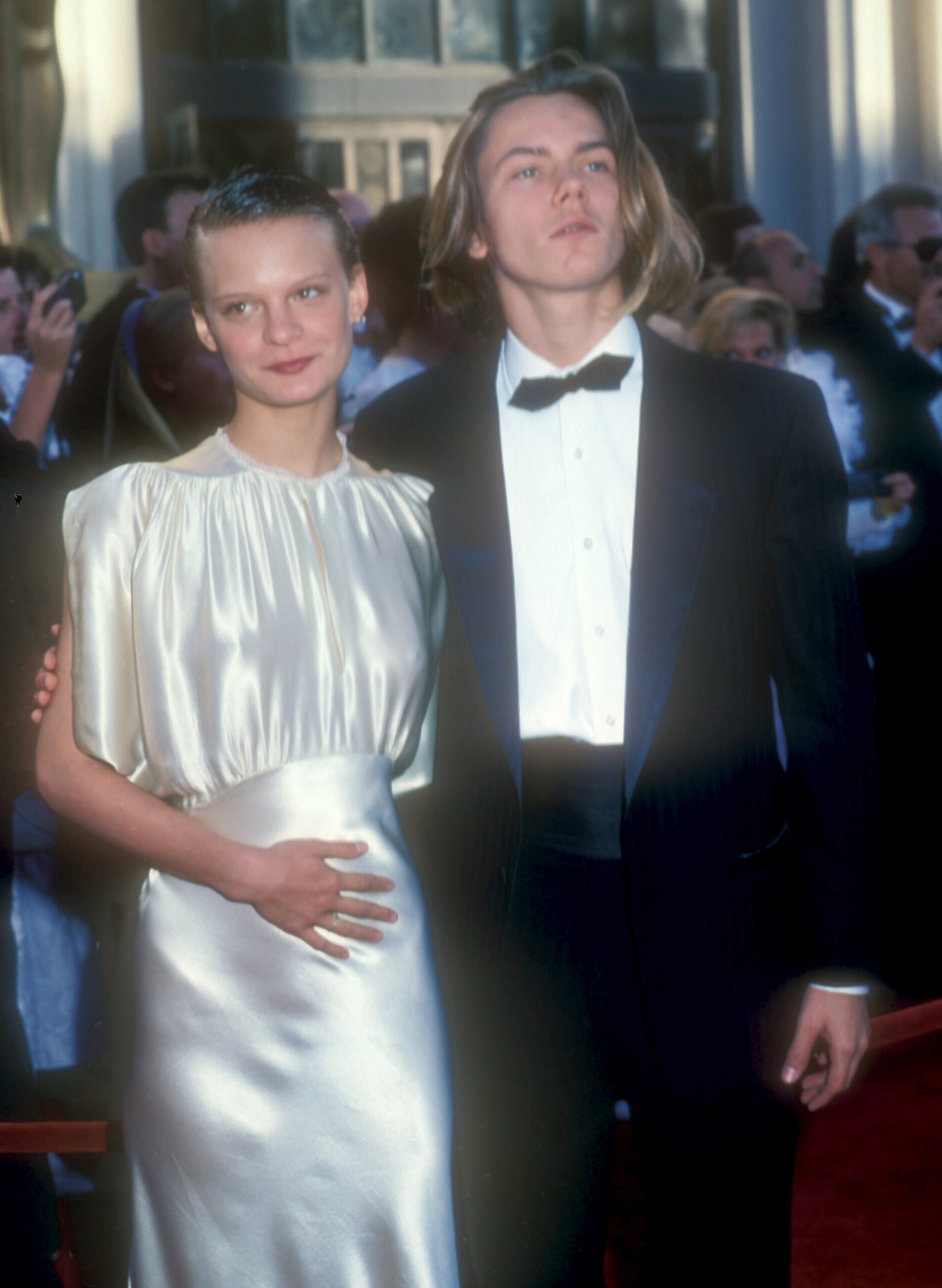 Martha and River walking the Academy Awards red carpet together, with Martha in a sleek dress with River in a suit