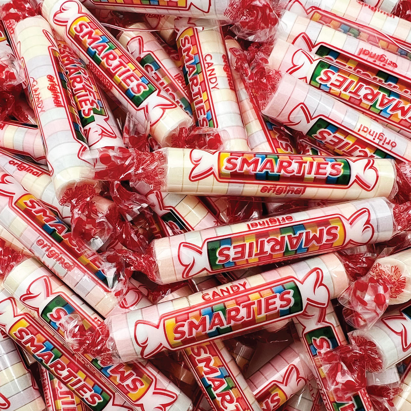 Rolls of Smarties candy piled together, showing colorful labels and clear packaging, in a playful arrangement