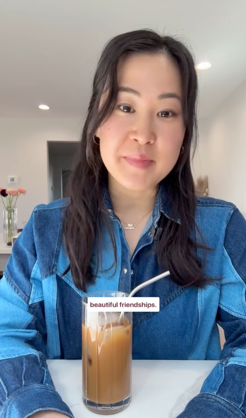 Person in a denim jacket smiles at the camera, standing behind a glass of iced coffee with the text "beautiful friendships."