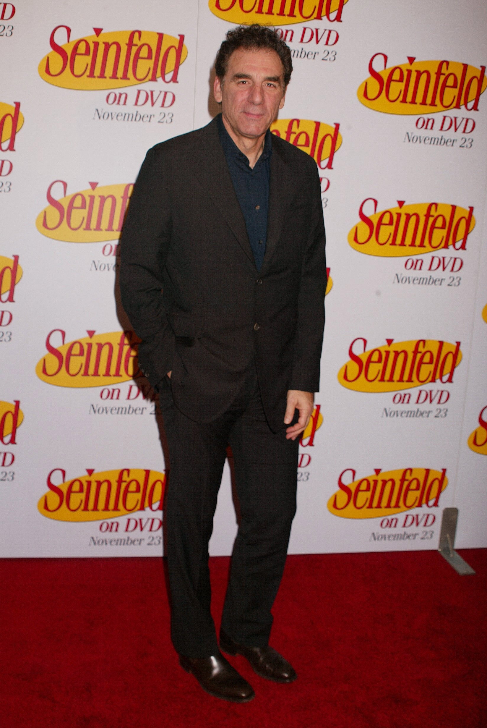 Man in a black suit on a red carpet at a "Seinfeld on DVD" event backdrop
