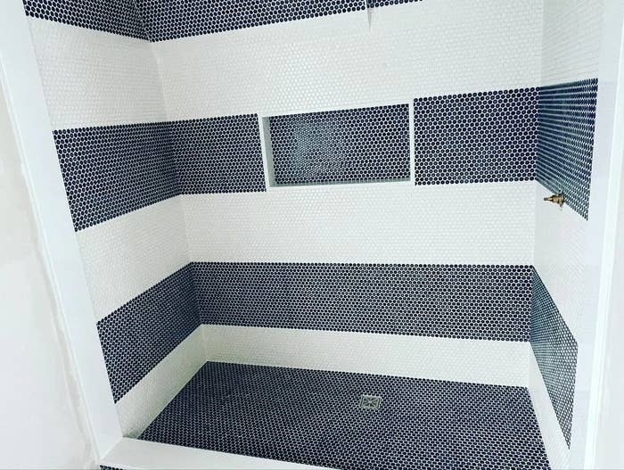 Shower interior with alternating dark and light tile bands and a built-in nook