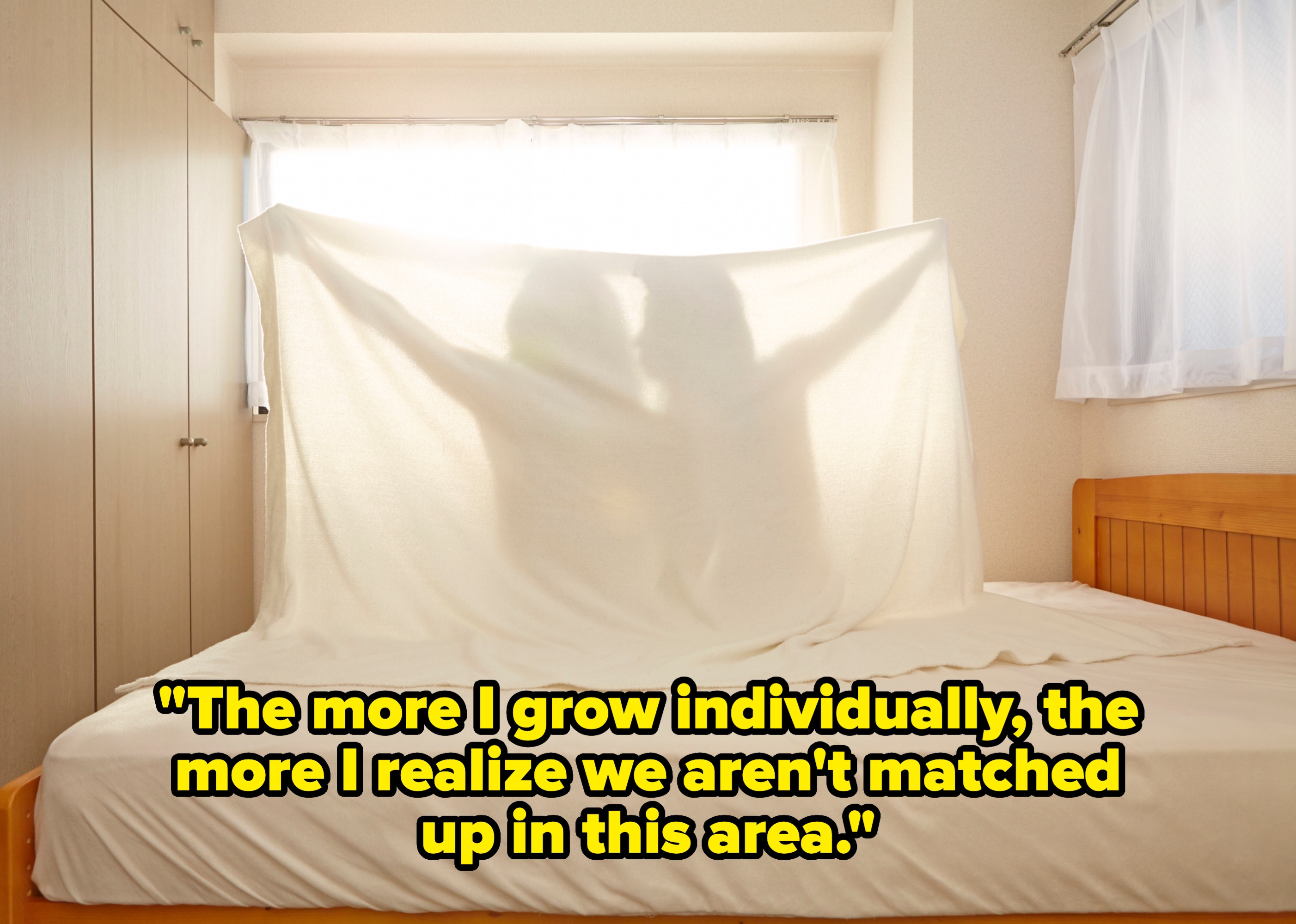 Two people embrace behind a backlit sheet on a bed, creating a shadow. Romantic and intimate mood