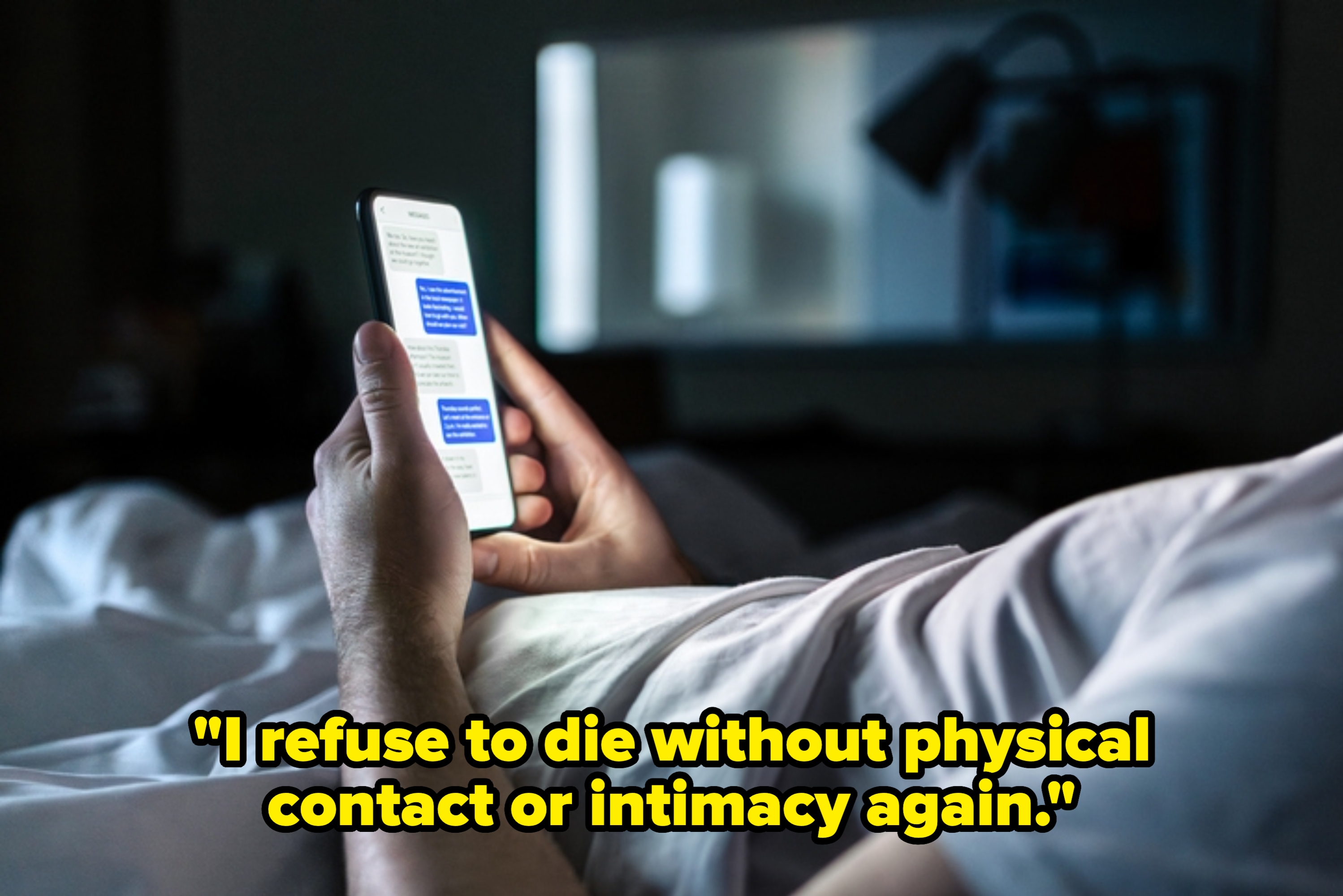Person lying in bed, holding a smartphone and reading text messages in a dimly lit room