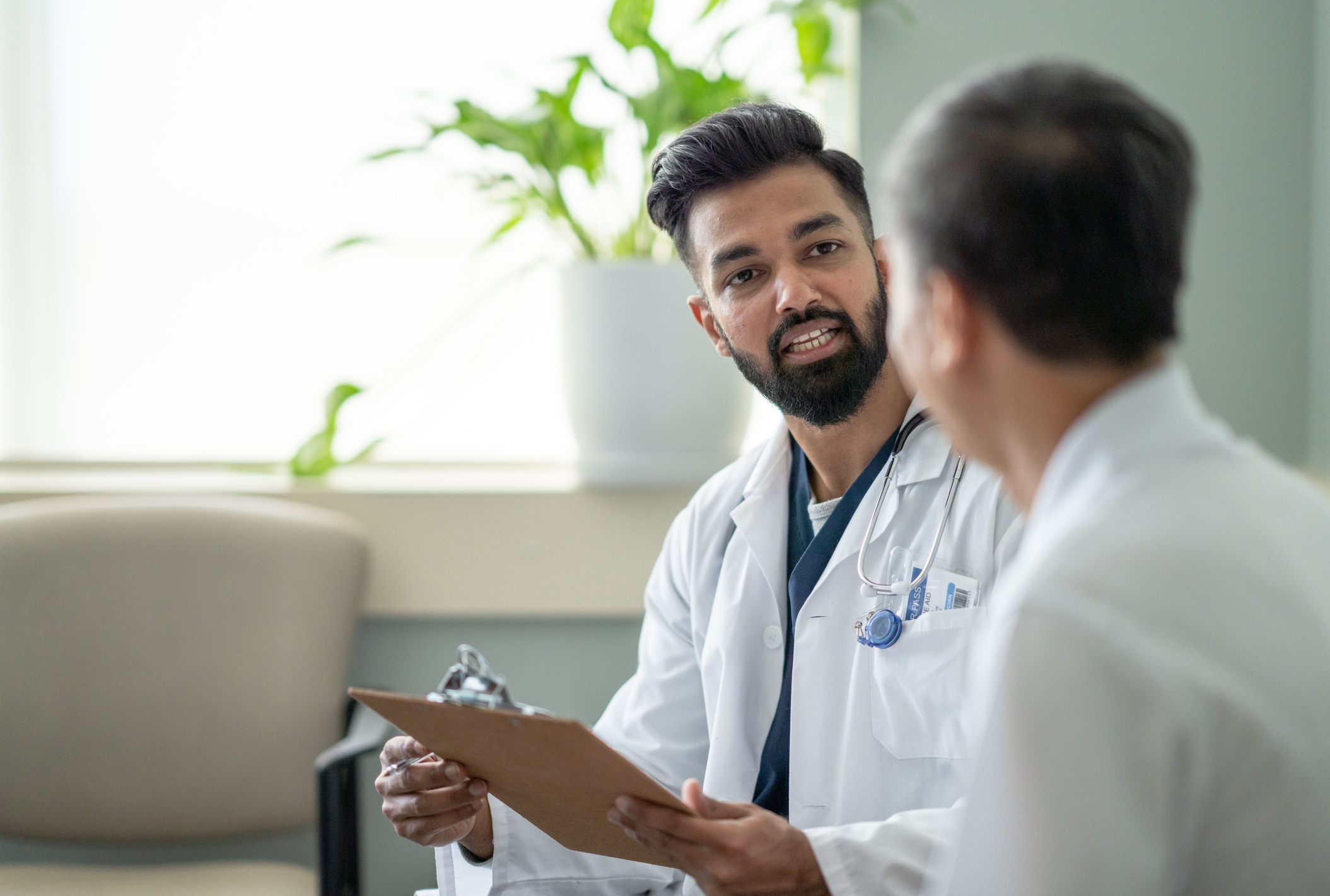 Two doctors in discussion, one holding a clipboard