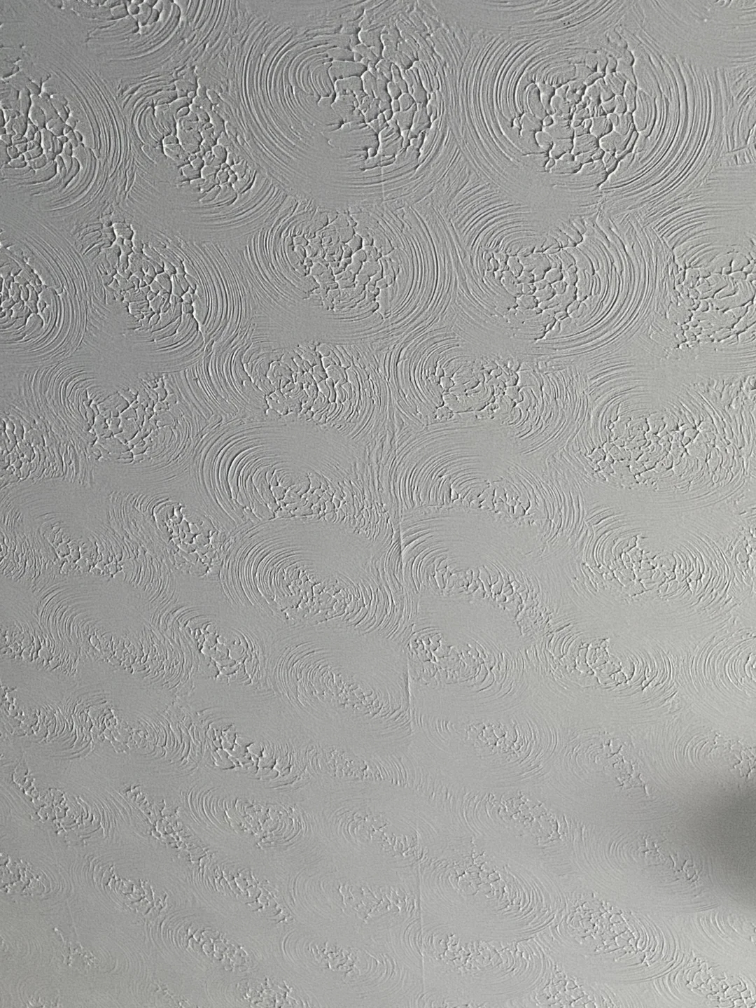 Textured ceiling with a swirled, circular pattern design. The image captures the intricate relief of the plasterwork