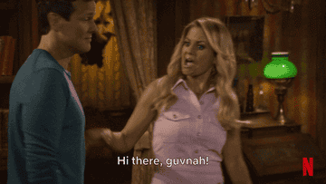 Woman in casual sleeveless shirt playfully greets a man indoors with, "Hi there, guvnah!" in a TV show scene