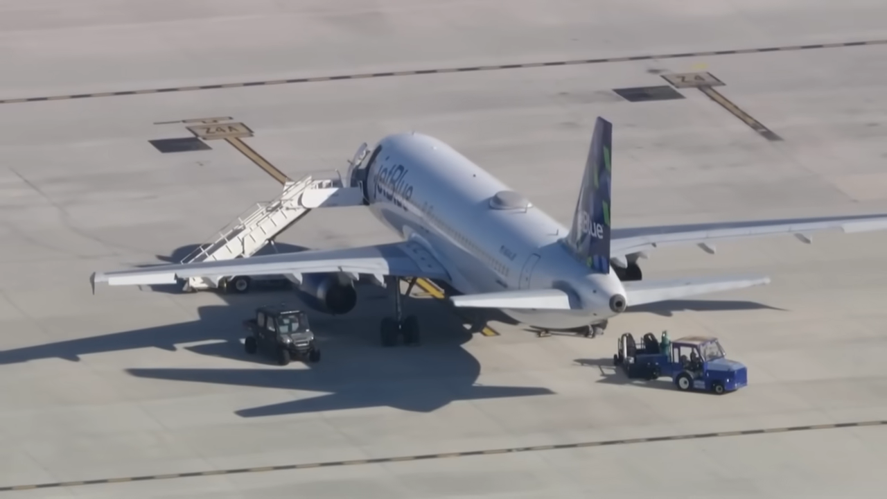 Airplane parked on tarmac with stair truck and service vehicles nearby, suggesting maintenance or boarding activities