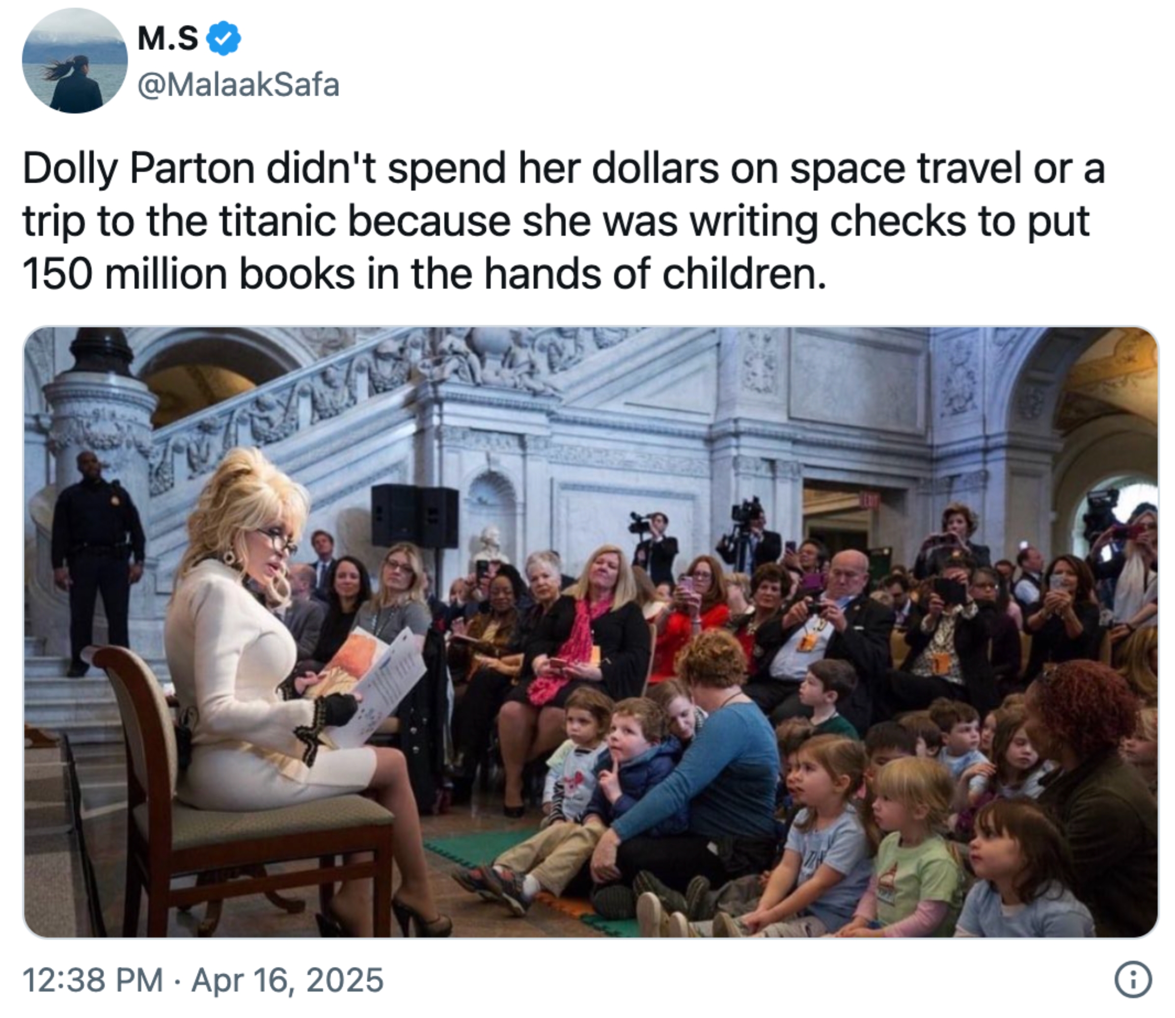 Dolly Parton reads to children in a library during a public event, surrounded by an attentive audience