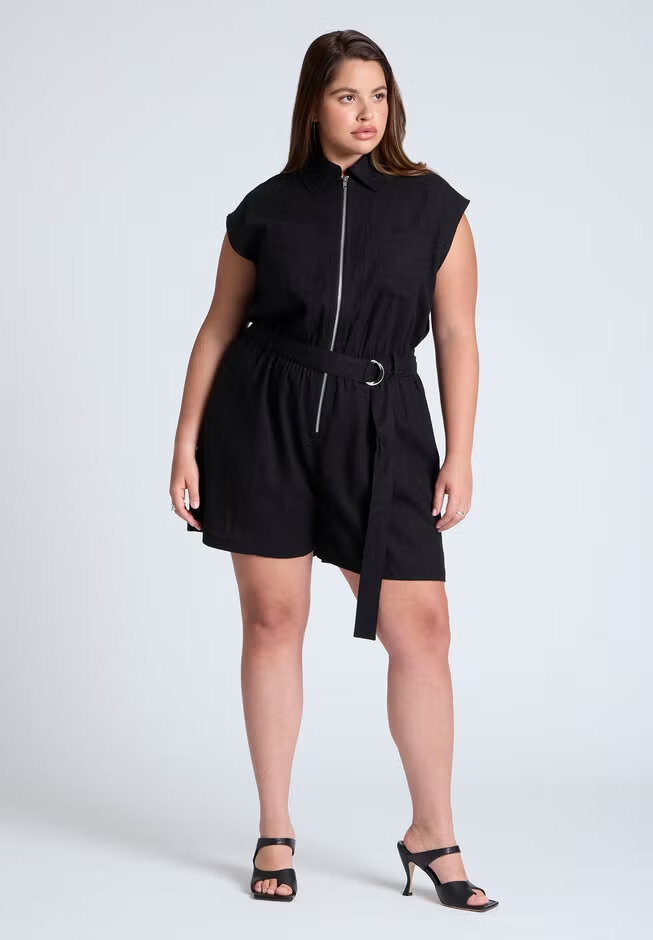 Person wearing a stylish belted romper with a zip and heeled sandals, posing confidently for a shopping article