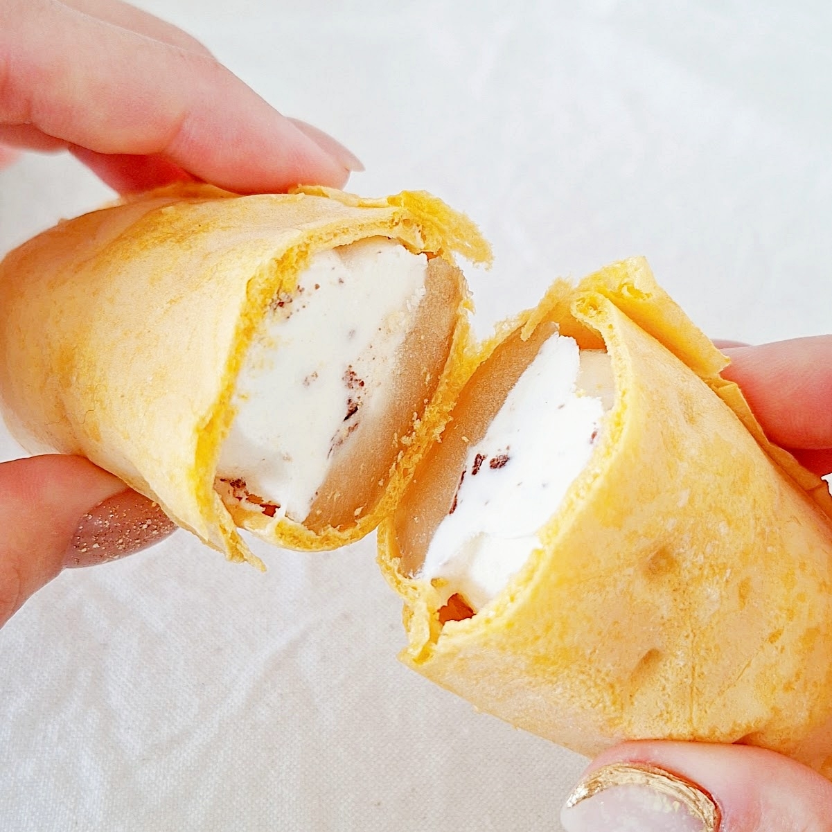 アイスクリームが入ったモナカを割っている手元。クリスピーな外側が見える。