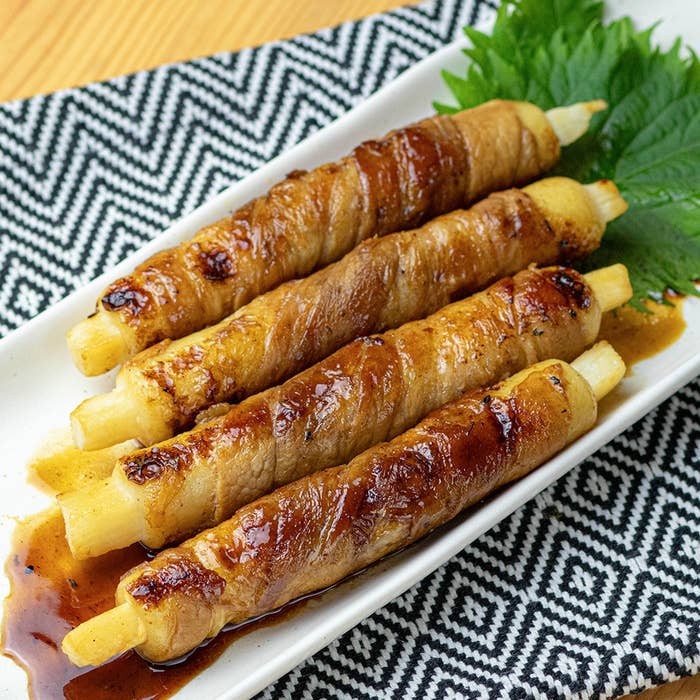 皿に盛られたアスパラの肉巻き。ジューシーな外観で、葉物が添えられている。