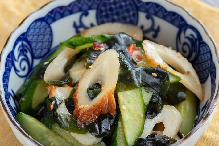 きゅうり、わかめ、ちくわを使った和風サラダが青い縁取りの器に盛られている。ゴマが飾られている。